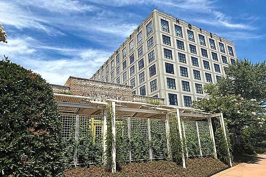 Proximity Hotel and Print Works Bistro facade late summer 2025. Garden Trellis provides abundant shade and a cool place to have a cocktail with friends.