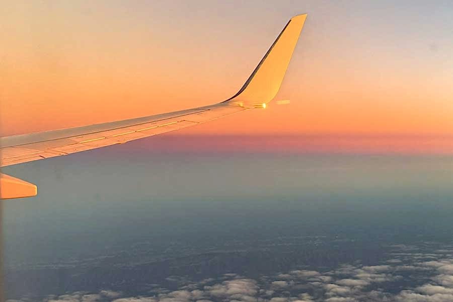 View from window seat on airplane as sun is setting.