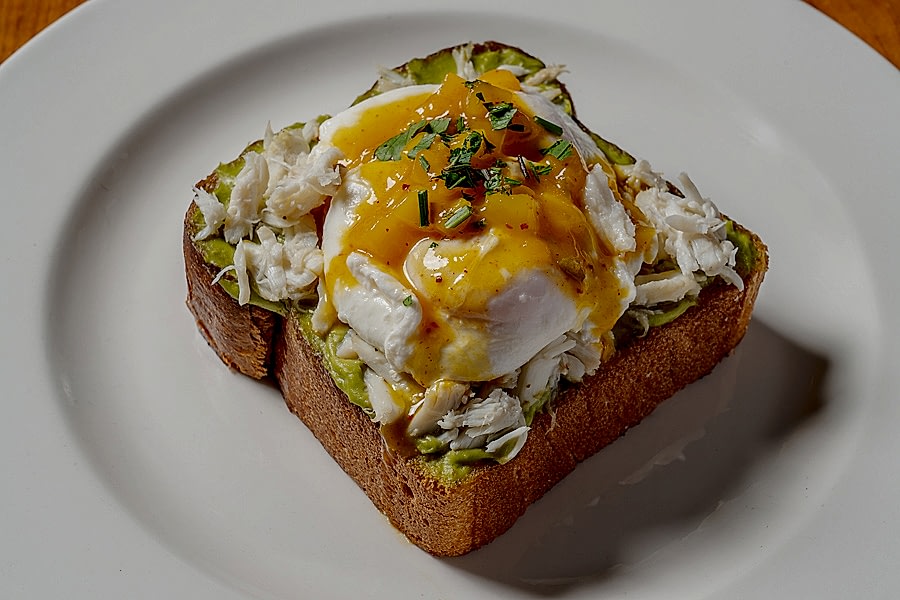 AVOCADO TOAST, challah, avocado mousse, blue crab, mango coulis, poached eggs, Greek yogurt, housemade granola