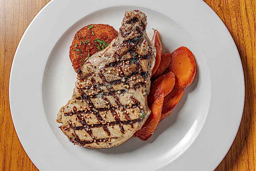 GRILLED PORK CHOP, mustard-tarragon butter, cheddar, bacon & chive potato cake, Vichy carrots